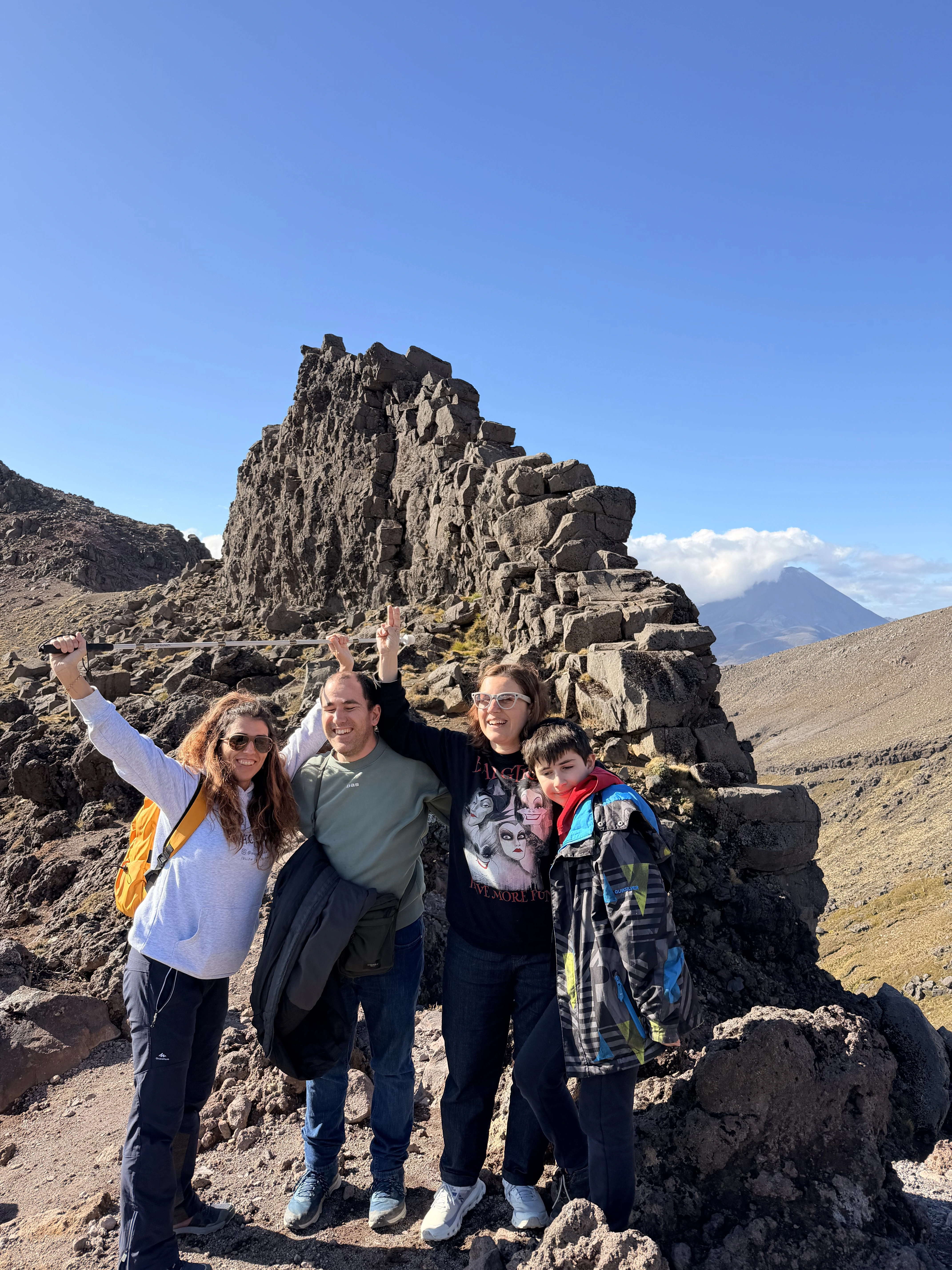Una viajera de Watchout Tours en lo alto de una montaña de Nueva Zelanda, con un amplio paisaje al fondo